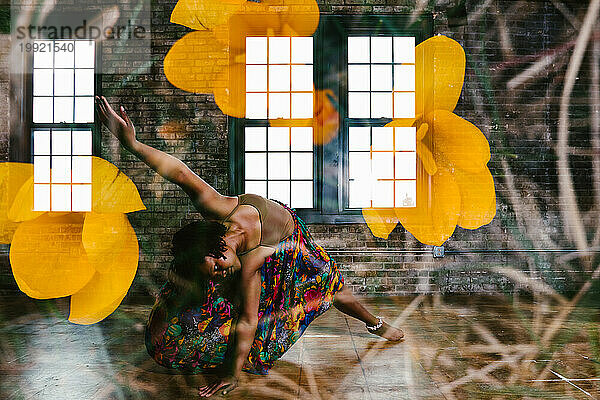 Schwarze Tänzerin posierte in einem Gebäude mit Blumen darüber
