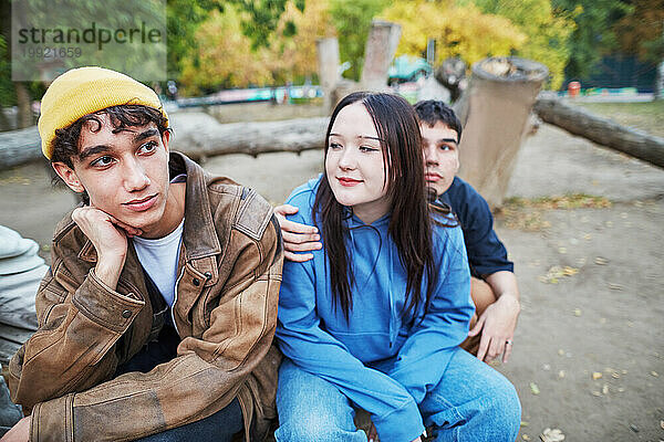 Junger Mann sitzt mit Freunden im Park von Angesicht zu Angesicht