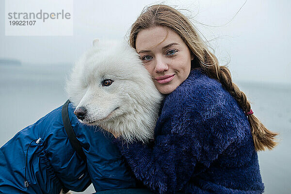 Mädchen geht mit einem weißen  flauschigen Samojedenhund in der Natur spazieren