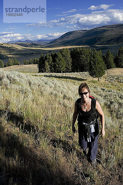 Eine erwachsene Frau lächelt  während sie durch das Lamar Valley im Yellowstone-Nationalpark  Wyoming  wandert.