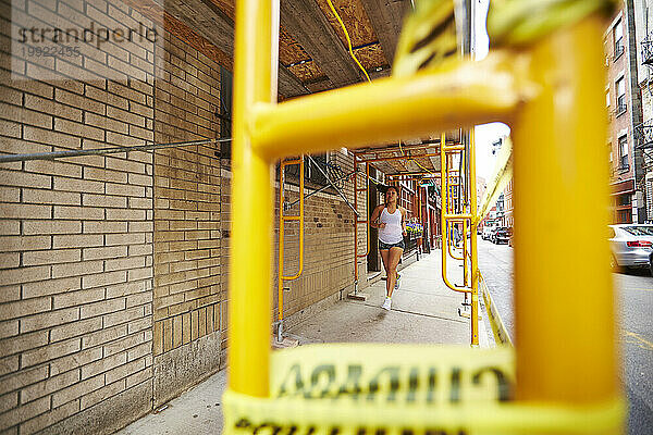 Eine junge asiatische Frau rennt an einer Baustelle auf einer Stadtstraße vorbei.