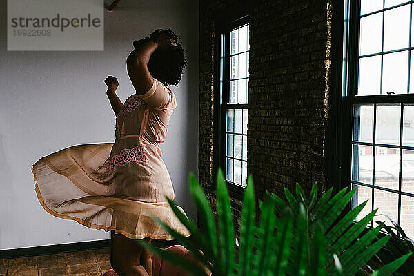 Tänzerin wirbelt im Kleid in einem Gebäude mit Ziegelsteinen und Fenstern