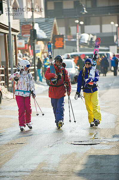 Drei Skifahrer gehen die Straße im italienischen Dorf Champoluc in Italien entlang.
