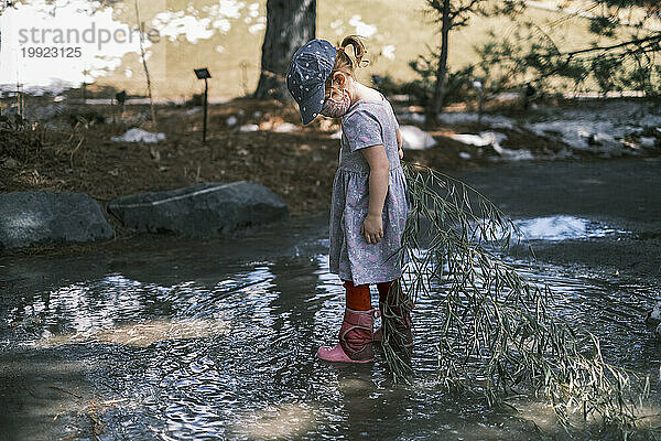 Kind spielt an einem nassen Tag in einer schlammigen Pfütze