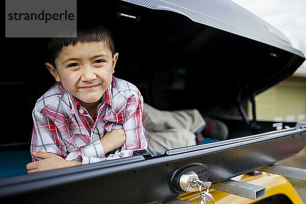 Junge lächelt und sitzt in einer Frachtkiste