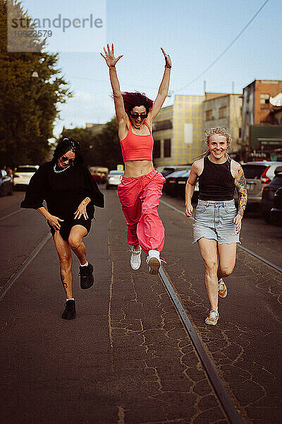 Drei glückliche Freundinnen rennen die Straße entlang und springen auf.