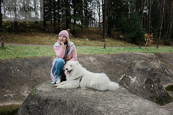 Junges Mädchen geht mit einem weißen  flauschigen Samojedenhund in der Natur spazieren