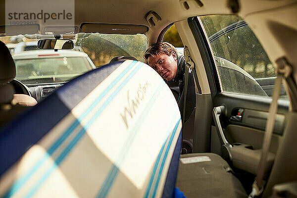 Ein Surfer nimmt ein Surfbrett  das im Auto aufbewahrt wird