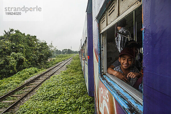 Junge lächelt und schaut durch das Fenster des Zuges der Yangon Central Railway  Yangon  Myanmar