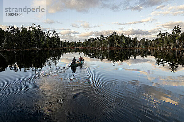Zwei Personen steuern ein Kanu durch die ruhigen Gewässer eines Sees in Maine