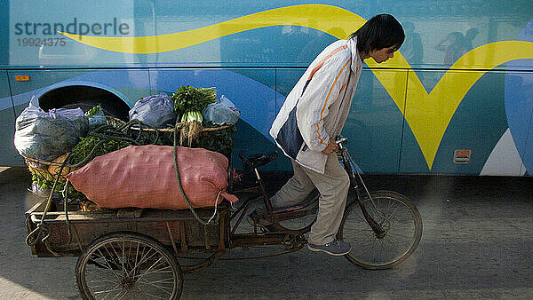 Eine Person mit einem Fahrrad  das Waren in der Provinz Yunnan  China  transportiert.