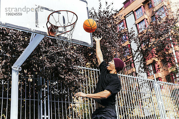 Multiethnischer Junge schießt Korb und spielt Basketball