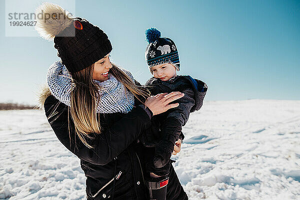 Frau lächelt Kind liebevoll an  während sie Winterkleidung und Mütze trägt
