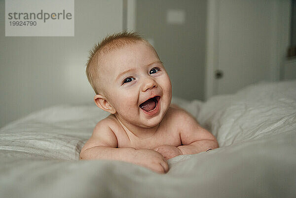 Nahaufnahme des Gesichts eines Babys  das breit lächelt und in die Kamera lacht