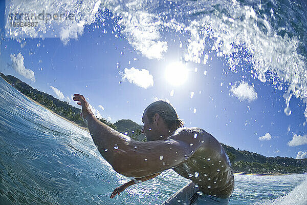 Eine sehr weite Wasseransicht eines jungen Mannes beim Surfen am Rocky Point  Nordküste von Oahu. Hawaii