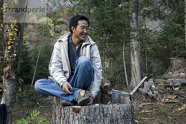 Ein Mann sitzt auf einem Baumstumpf in der Provinz Yunnan  China.