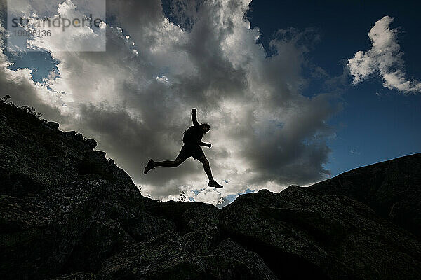 Silhouette eines männlichen Wanderers springt zwischen Felsen  Mount Katahdin  Maine