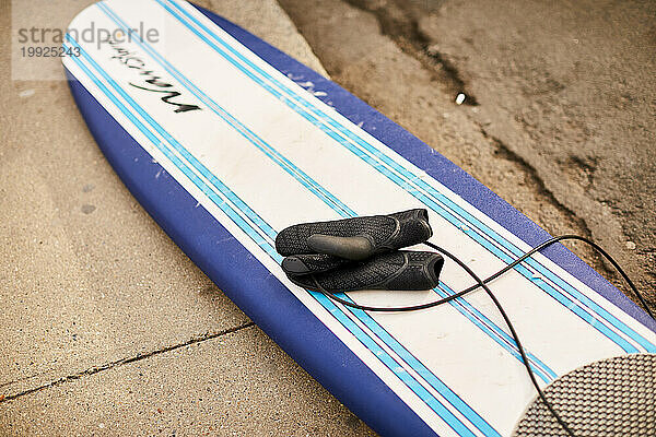 Ein Surfbrett mit Neoprenhandschuhen am Strand