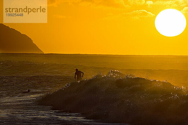 Surfen bei untergehender Sonne auf Hawaii