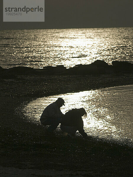 Die Silhouette eines Paares vor glitzerndem Wasser am Strand in Hyannis  Massachusetts.