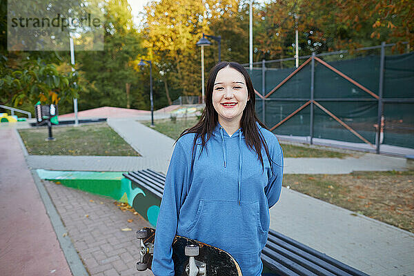 Lachendes Mädchen mit Skateboard im Skatepark