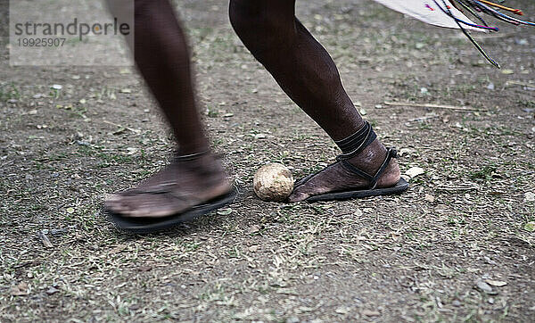 Ein Tarahumara-Indianer wirft während einer Rarj'paro-Partie eine Holzkugel mit den Füßen.