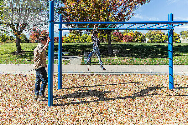 Vater beobachtet Sohn beim Klettern am Spielplatz