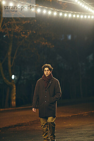 Stilvoller junger Mann draußen in der Stadt bei Nacht