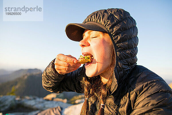 Aktive Frau isst Chips und Salsa im Freien  am Berg.