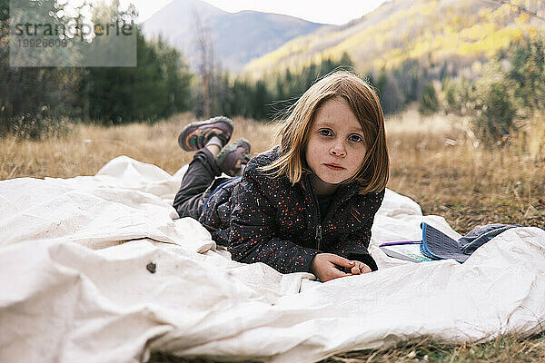 Junges Mädchen liegt draußen  umgeben von Bergen