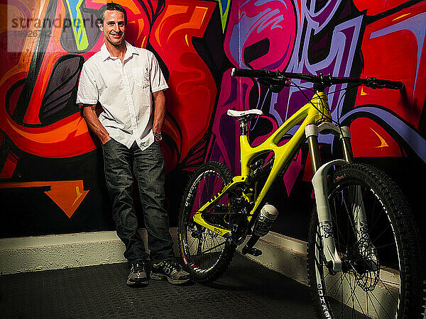 Mann steht drinnen neben einem Fahrrad und einer mit Graffiti bedeckten Wand  Laguna Beach  Kalifornien  USA