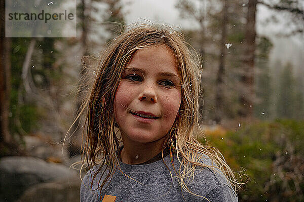 Porträt eines Teenagers draußen im Schneefall mit Schnee im Haar