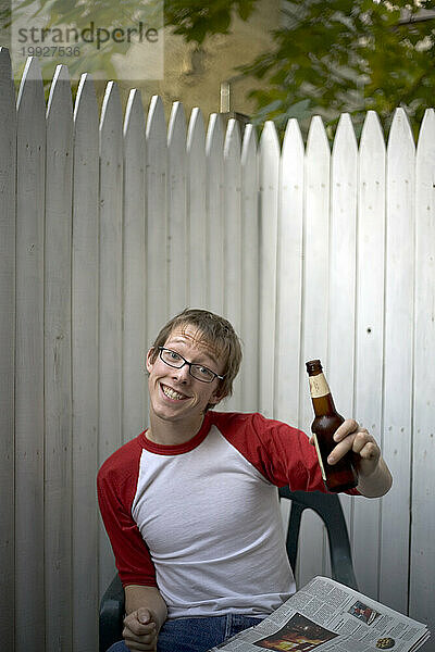 Junger Mann trinkt Bier im Hinterhof.
