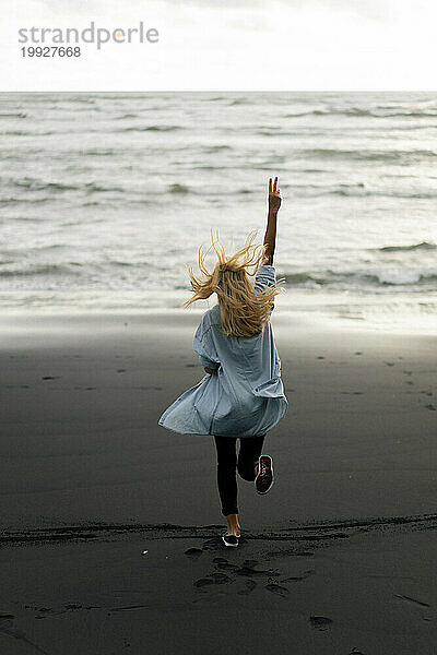 Glückliche Frau am Strand rennt zum Meer.