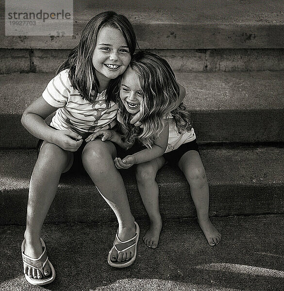Glückliche junge Schwestern  die sich umarmen und lächeln