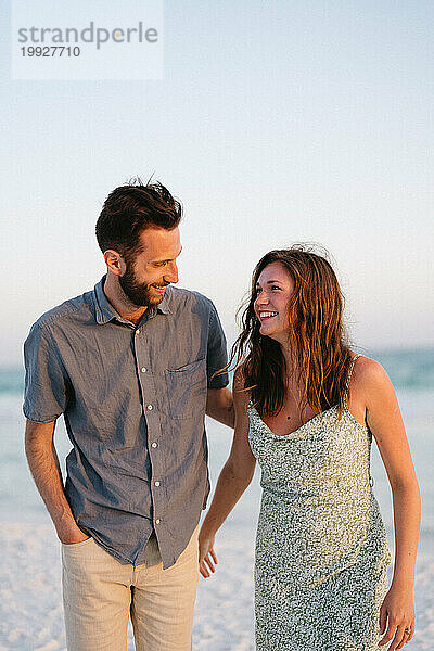 Bruder und Schwester lächeln sich im Urlaub am Strand an