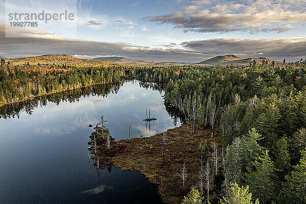 Ein friedlicher See bei Sonnenaufgang tief in den Wäldern von Maine im Herbst.