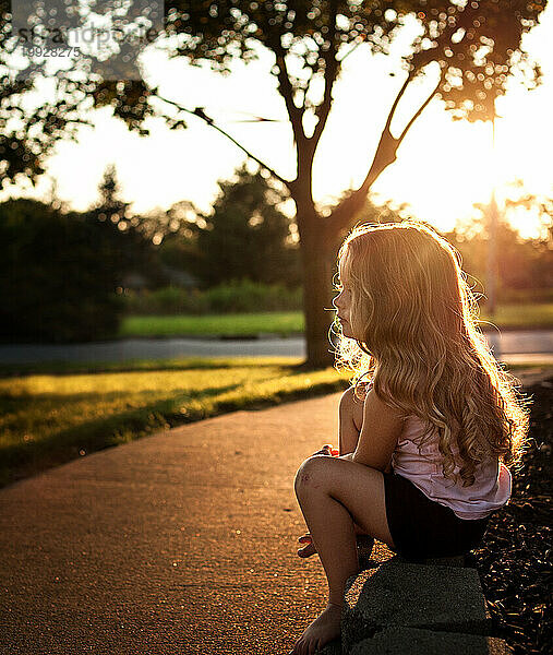 Schönes kleines Mädchen mit langen Locken draußen im Sommer