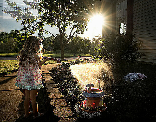 Junges Mädchen bewässert den Garten an einem sonnigen Tag