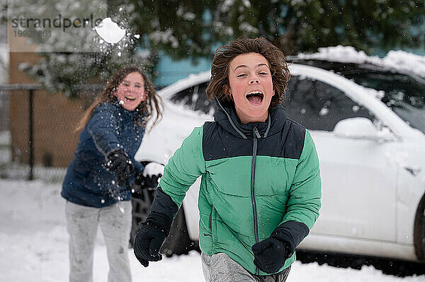 Fröhliche Teenager-Brüder bei einer Schneeballschlacht im Winter