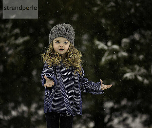 Schönes kleines Mädchen  das Schneeflocken fängt