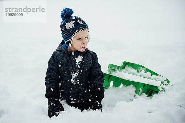 Nahaufnahme eines Kleinkindes  das draußen zu Hause im Schnee spielt  während es isst