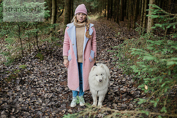 Junges Mädchen geht mit einem weißen  flauschigen Samojedenhund in der Natur spazieren