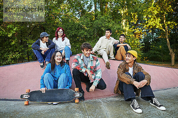 Gruppe von Teenagern mit einem Skateboard  die in einem Skatepark sitzen