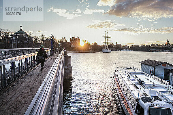 Menschen  die über eine Brücke über den Fluss und ein Boot in der Nähe gehen  Stockholm  Schweden