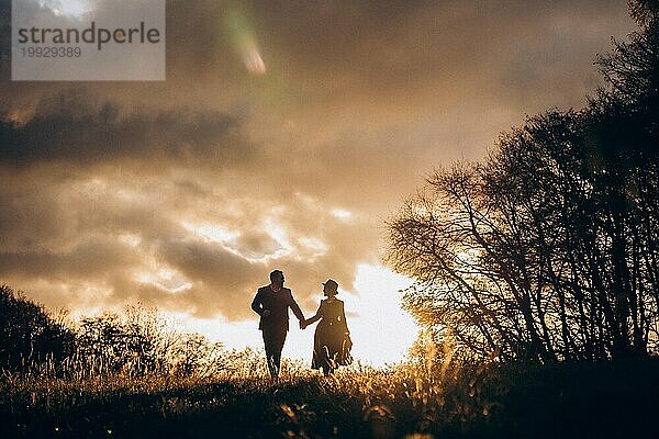Verliebtes Paar in historischen Kostümen im Herbstwald bei Sonnenaufgang