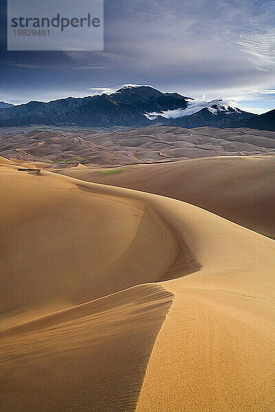 Direktes Sonnenlicht beleuchtet den Great Sand Dunes National Park & ??Preserve  während im Hintergrund der Mt. Herard auftaucht.