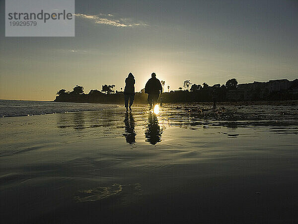 Zwei Personen am Strand in Santa Barbara  Kalifornien bei Sonnenuntergang. (von hinten beleuchtet)
