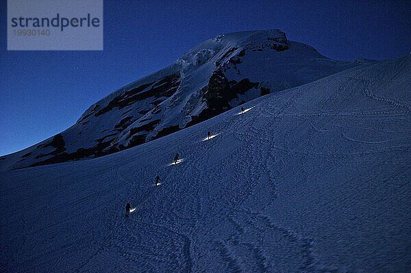 Bergsteiger mit Stirnlampen erklimmen den Mount Baker  während die Sonne aufgeht