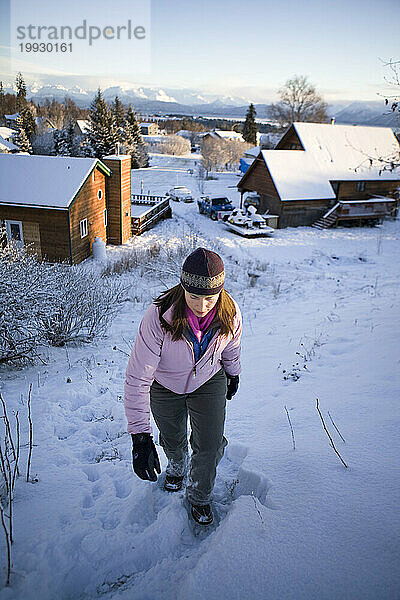 Eine erwachsene Frau verlässt die Nachbarschaft  während sie in Homer  Alaska  durch den Schnee wandert.